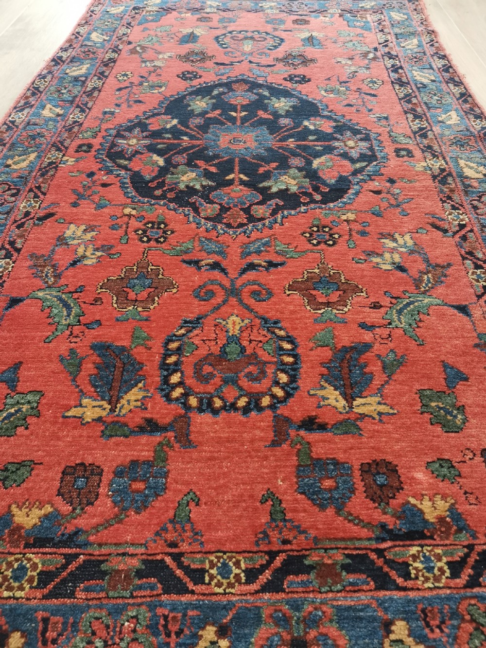 A hand-knotted antique Persian Hamadan rug featuring a central navy blue medallion on a red field framed by patterned borders. View VI