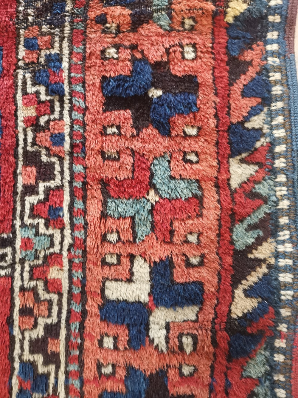 An antique East Anatolian Kurdish wool rug featuring a red ground with three large geometric medallions in indigo blue, framed by intricate tribal borders. View IV