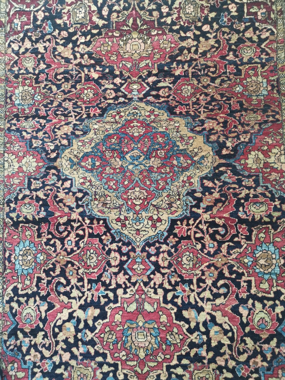 A rectangular hand-knotted Persian Isfahan rug featuring a central medallion with intricate floral arabesques in navy, deep red, and beige tones. View II