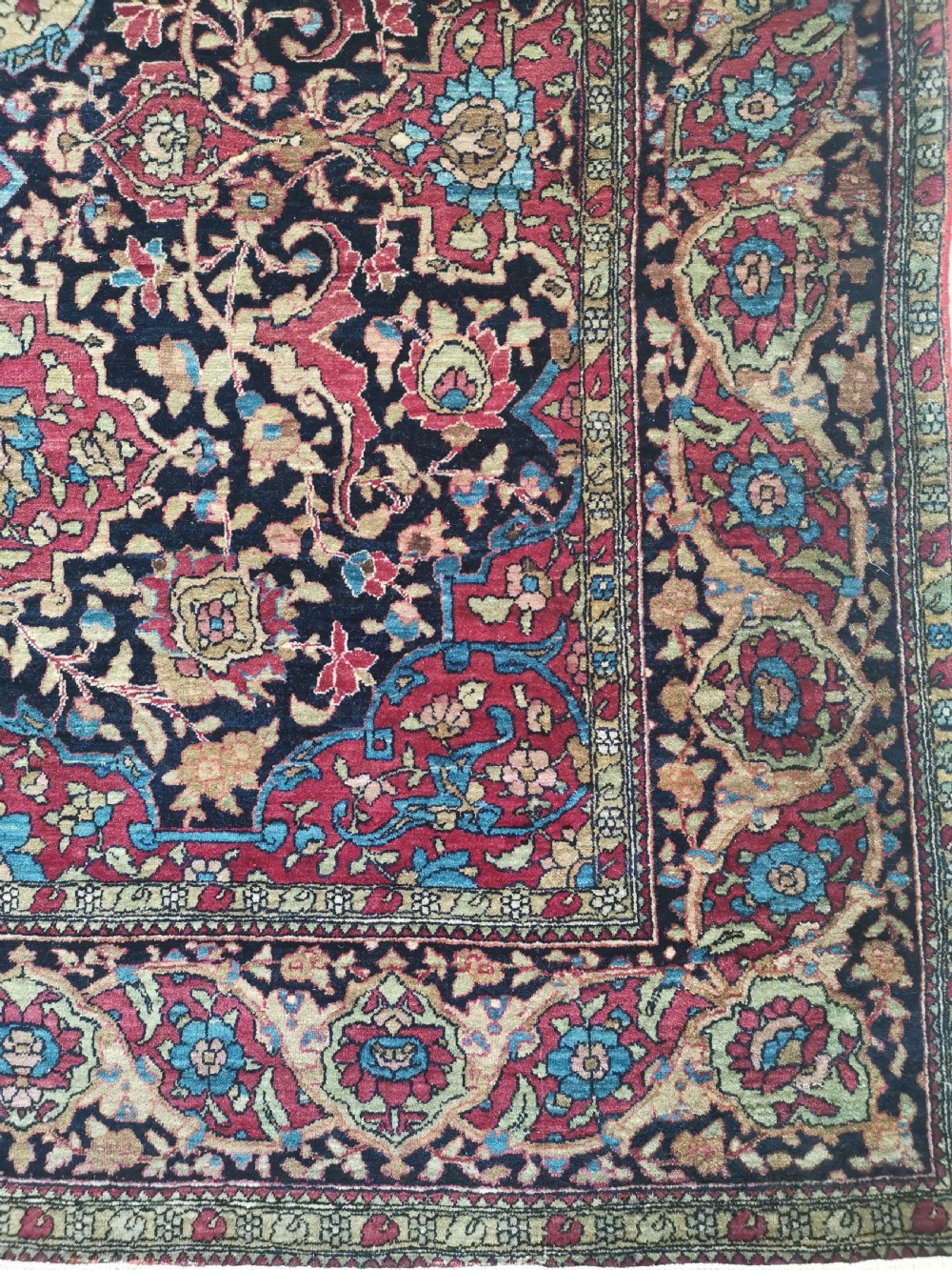A rectangular hand-knotted Persian Isfahan rug featuring a central medallion with intricate floral arabesques in navy, deep red, and beige tones. View V