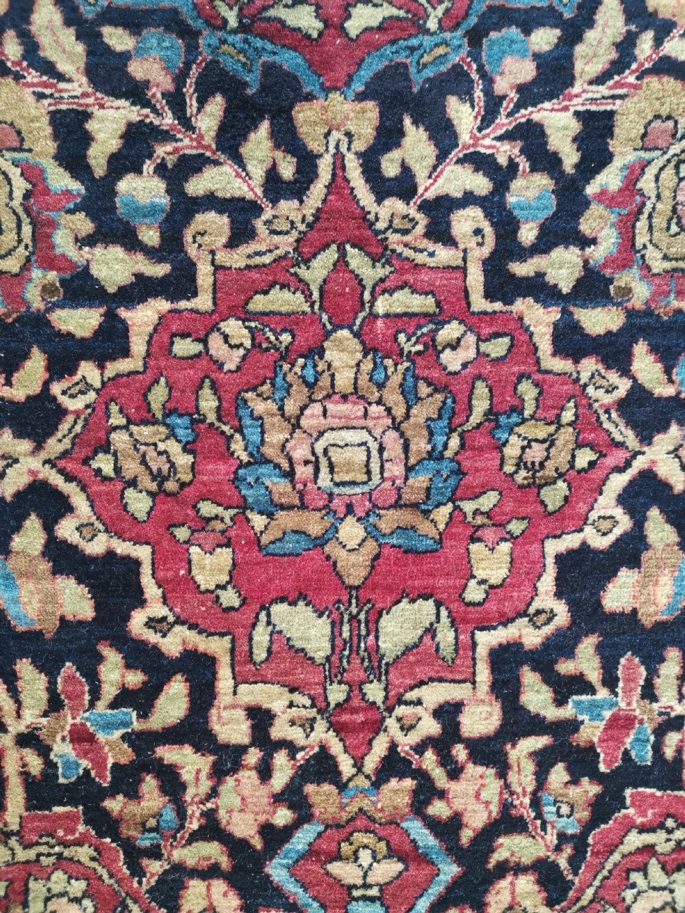 A rectangular hand-knotted Persian Isfahan rug featuring a central medallion with intricate floral arabesques in navy, deep red, and beige tones. View VII