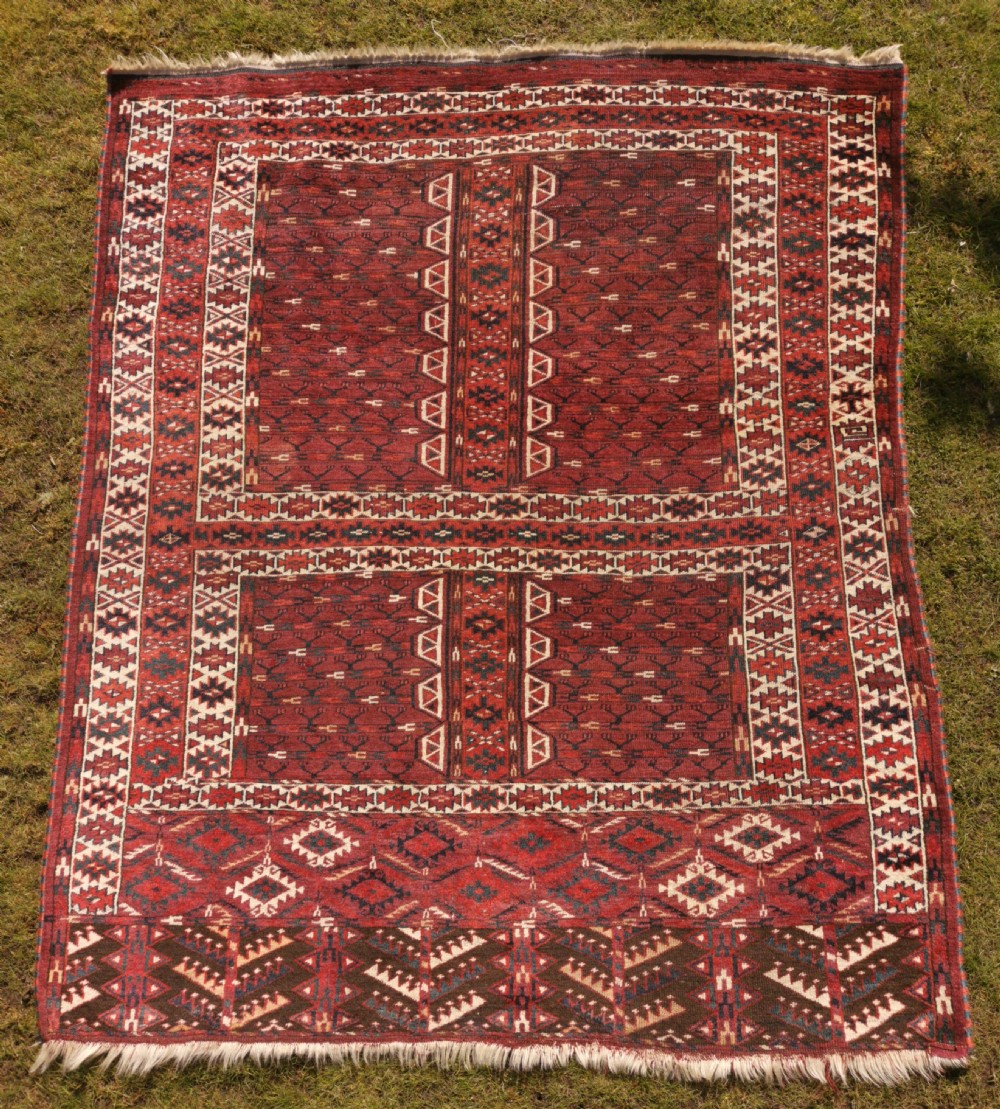 A hand-knotted dark red Yomud Engsi wool rug featuring a cruciform central pattern, geometric borders, and a patterned lower elem skirt.