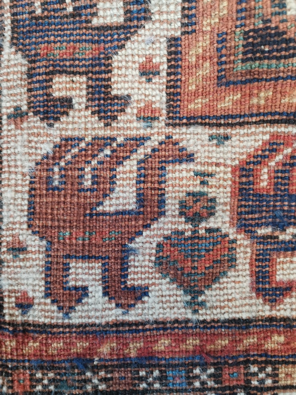 A rectangular hand-knotted wool rug featuring a dark navy central field with a large blue geometric medallion, surrounded by stylised bird motifs and a cream pattern border. View VI