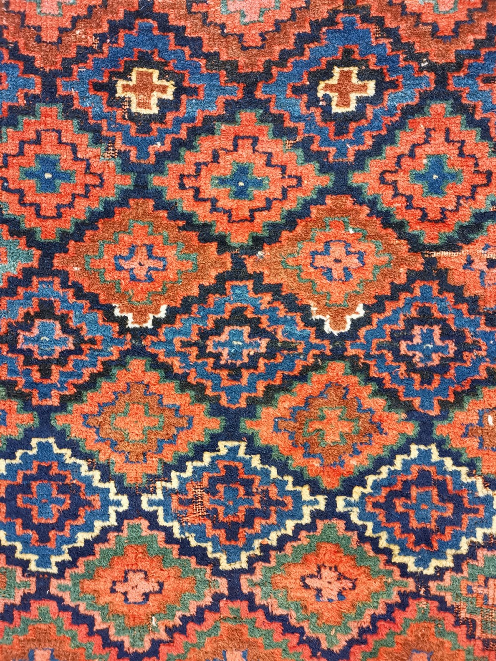 An antique Shahsavan handwoven wool runner featuring a red and navy blue geometric diamond lattice pattern surrounded by multi-coloured borders. View II