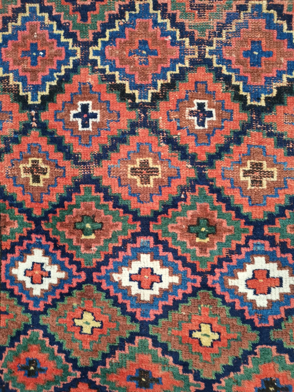An antique Shahsavan handwoven wool runner featuring a red and navy blue geometric diamond lattice pattern surrounded by multi-coloured borders. View III