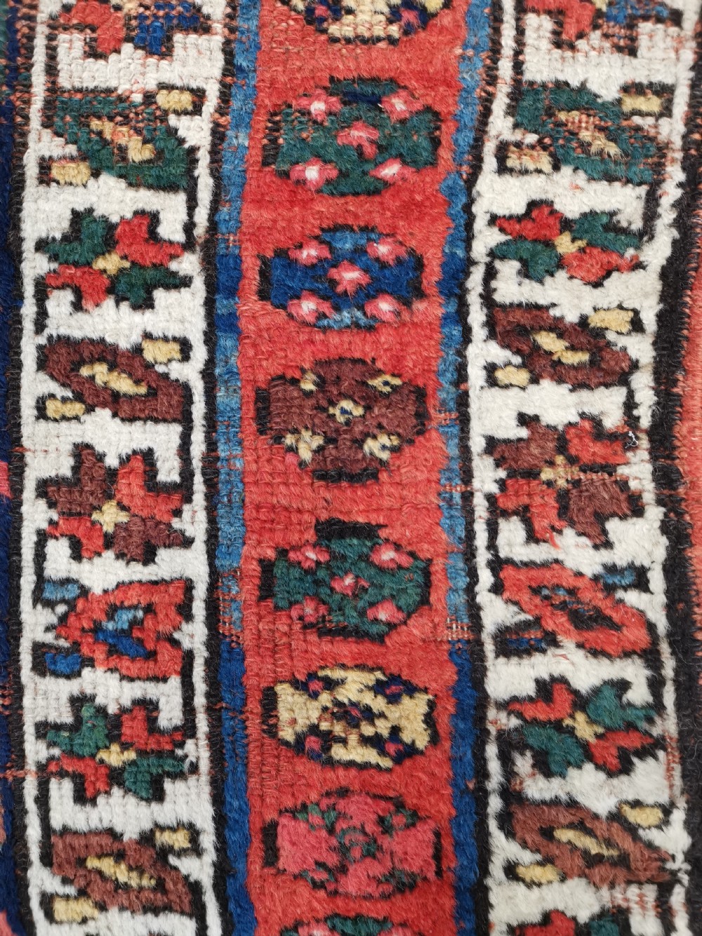 An antique Shahsavan handwoven wool runner featuring a red and navy blue geometric diamond lattice pattern surrounded by multi-coloured borders. View IV