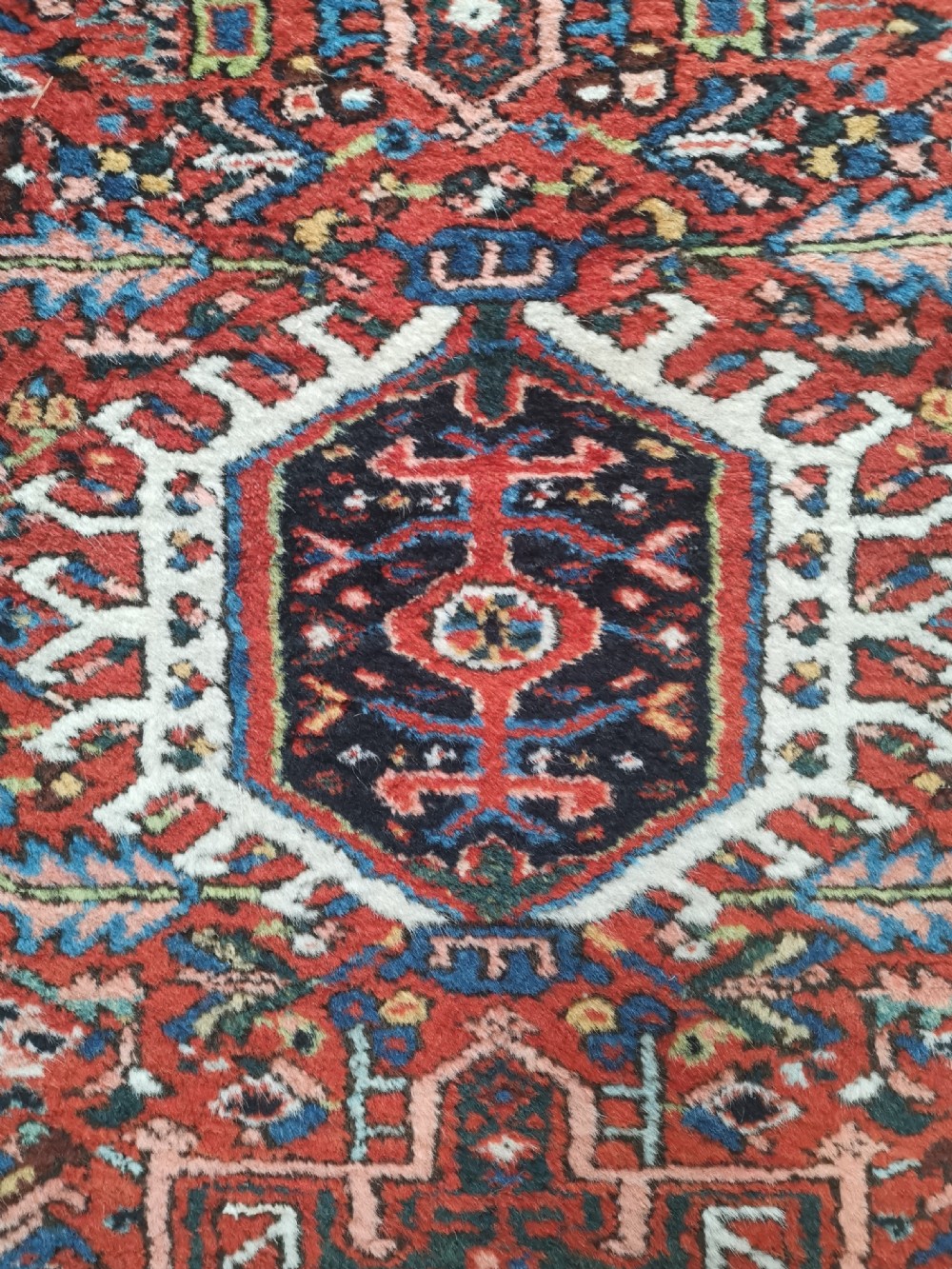 A hand-knotted wool Karaja rug featuring a primary red field with three central geometric medallions, surrounded by multi-layered borders in navy, green, and ivory tones. View II