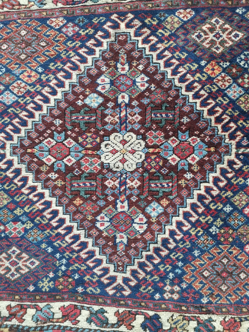 A square hand-knotted wool Qashqai bagface featuring a central geometric diamond medallion surrounded by patterned borders in red, navy blue, and cream shades. View II