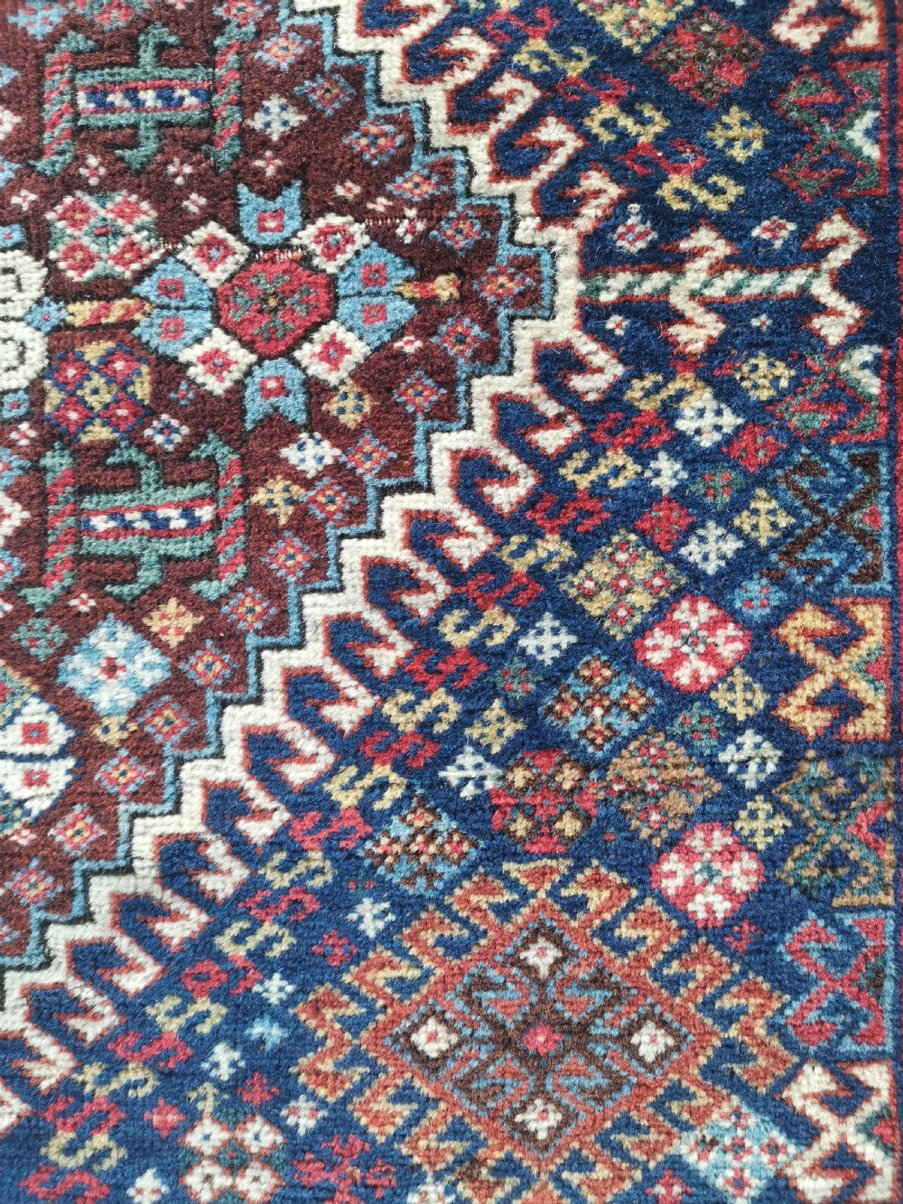 A square hand-knotted wool Qashqai bagface featuring a central geometric diamond medallion surrounded by patterned borders in red, navy blue, and cream shades. View IV
