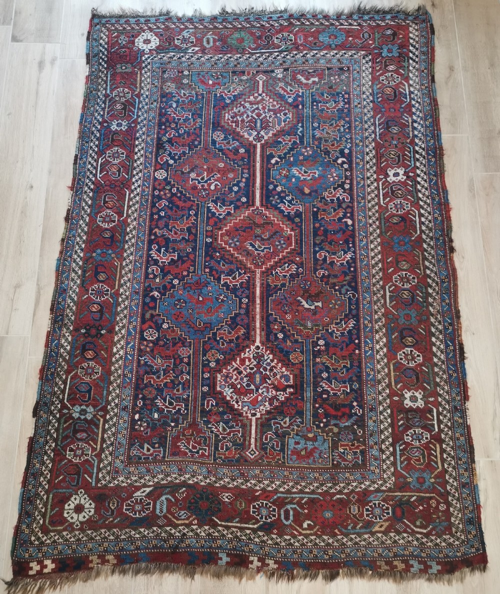 An antique Khamseh hand-knotted wool rug featuring geometric diamond medallions, stylized bird motifs, and a rich navy blue and madder red palette.