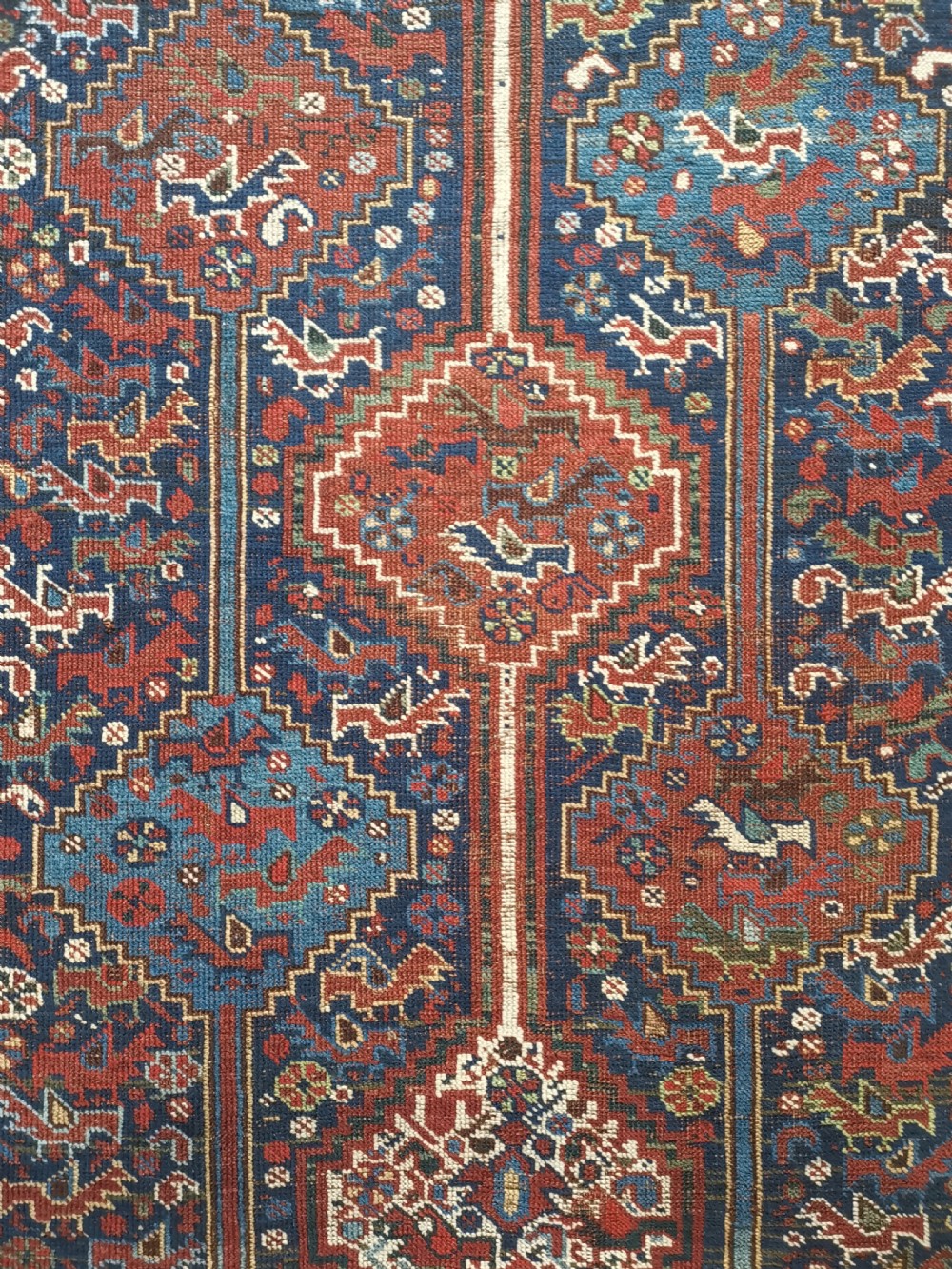 An antique Khamseh hand-knotted wool rug featuring geometric diamond medallions, stylized bird motifs, and a rich navy blue and madder red palette. View II