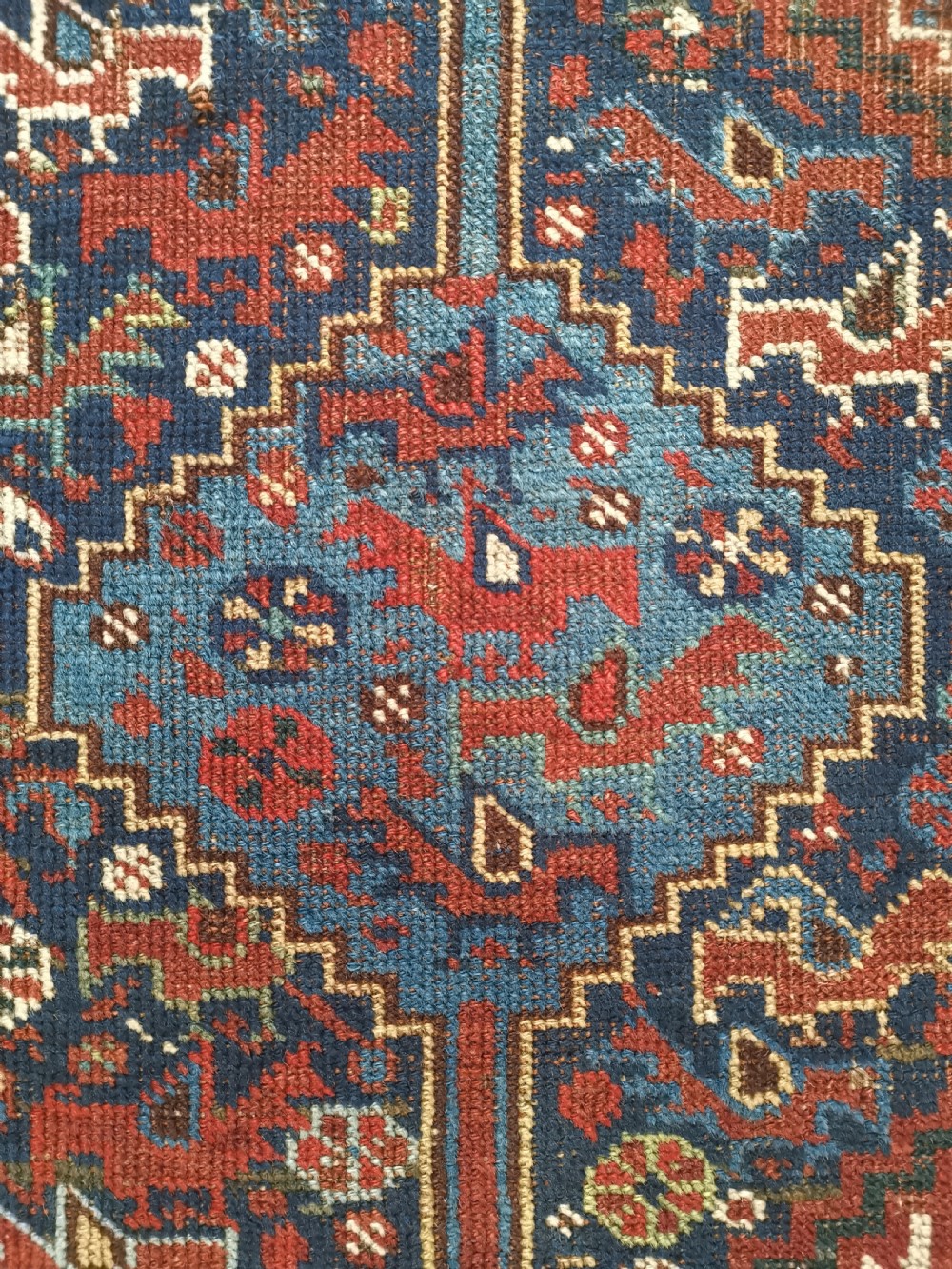 An antique Khamseh hand-knotted wool rug featuring geometric diamond medallions, stylized bird motifs, and a rich navy blue and madder red palette. View V