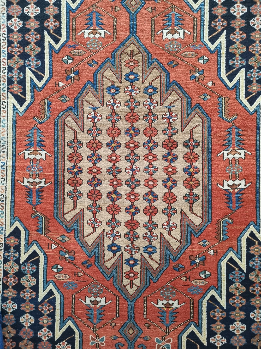 A hand-knotted Mazlaghan wool rug featuring a terracotta stepped central medallion surrounded by a dark blue geometric field and intricate multi-layered borders. View II