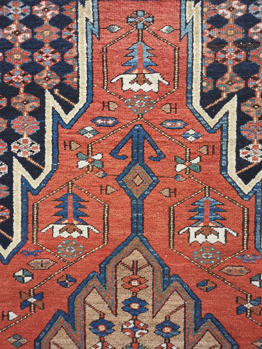 A hand-knotted Mazlaghan wool rug featuring a terracotta stepped central medallion surrounded by a dark blue geometric field and intricate multi-layered borders. View III