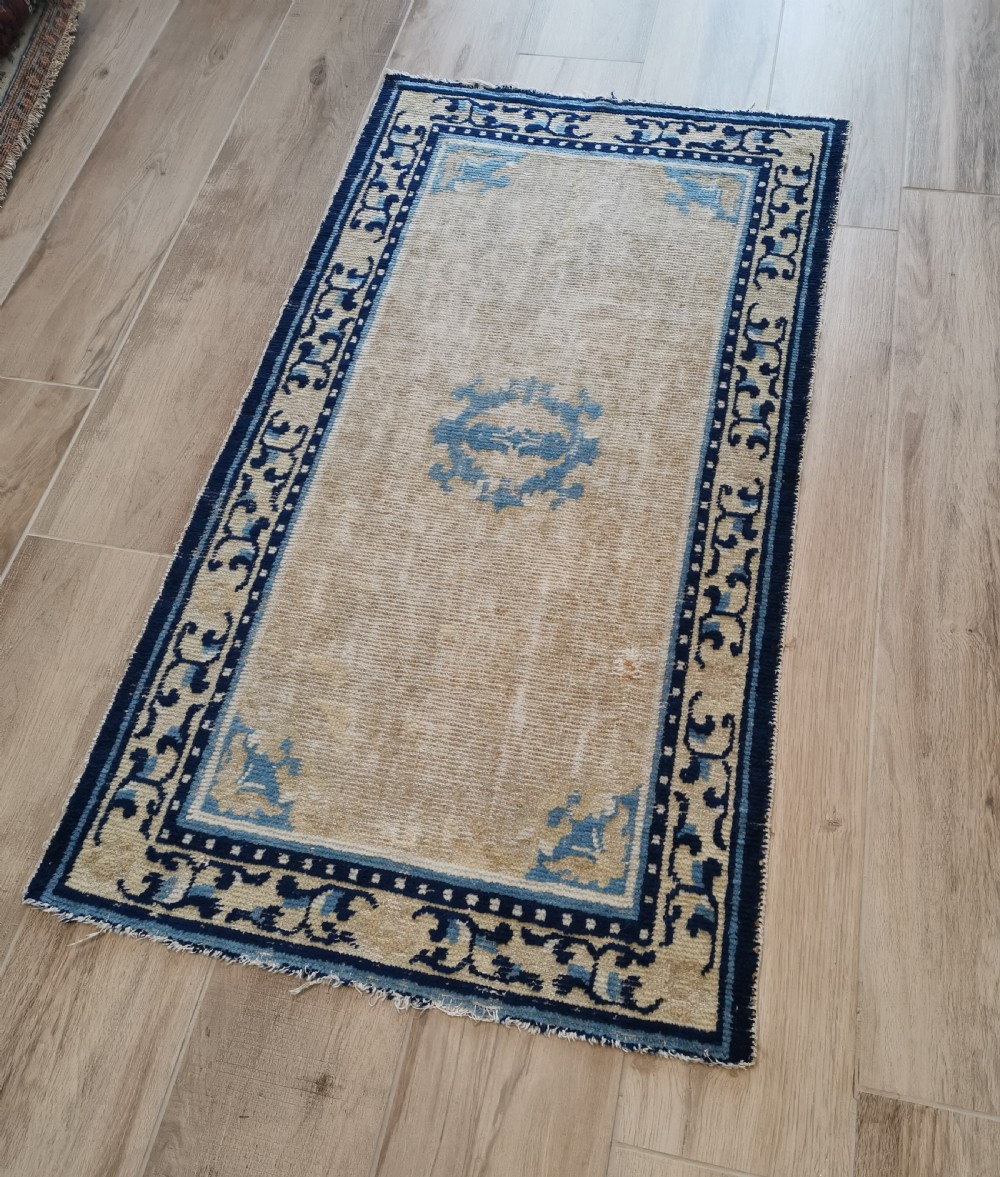 A hand-knotted antique Ningxia rug featuring a beige wool field, central blue medallion, corner motifs, and a repeating scrolling blue border. View III