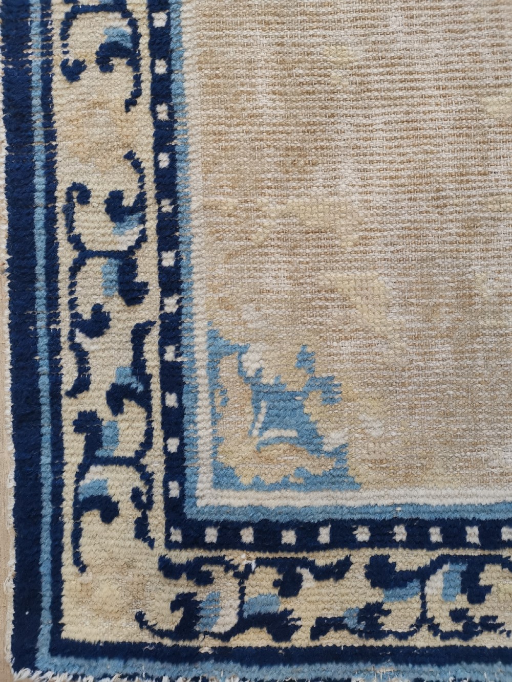 A hand-knotted antique Ningxia rug featuring a beige wool field, central blue medallion, corner motifs, and a repeating scrolling blue border. View IV