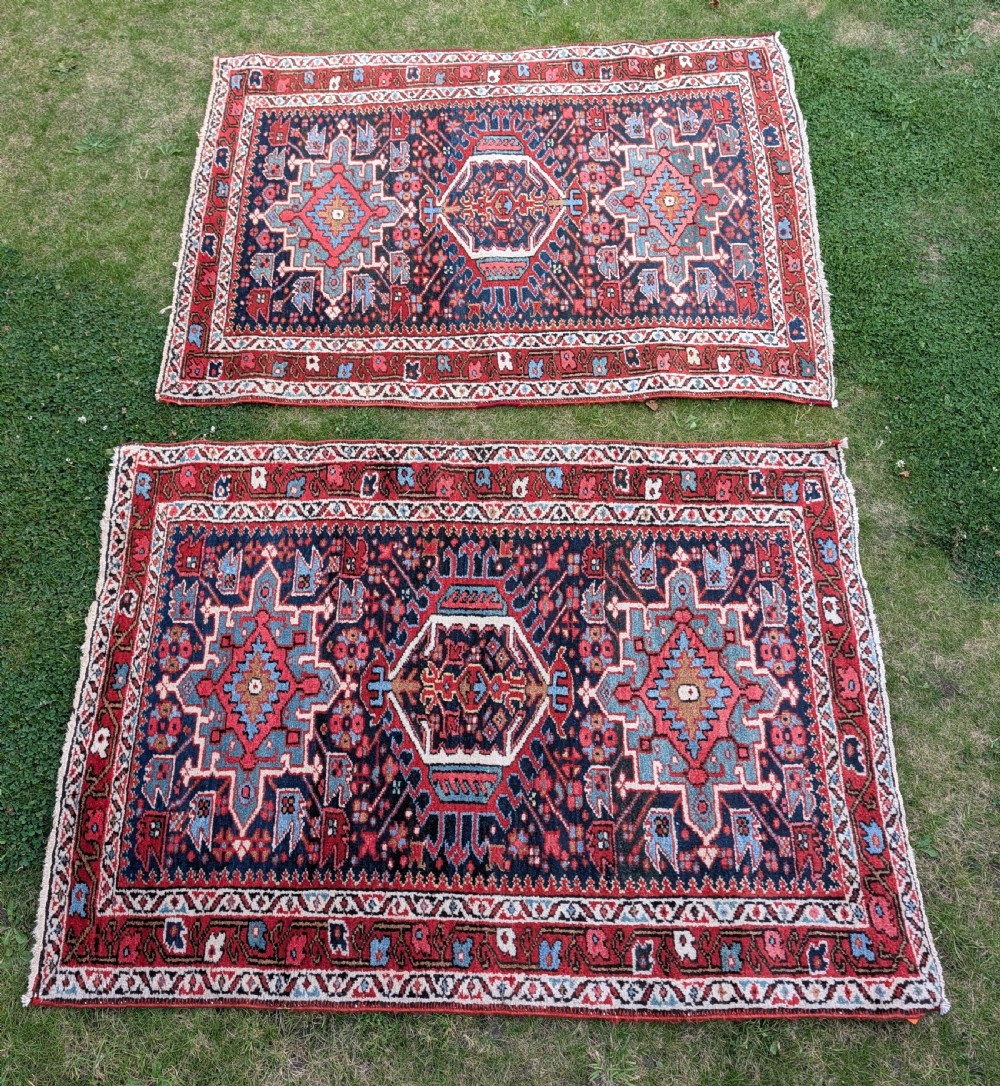 A pair of hand-knotted wool Karaja rugs featuring traditional geometric central medallions in blue, red, and ivory on an indigo field with stylized borders.