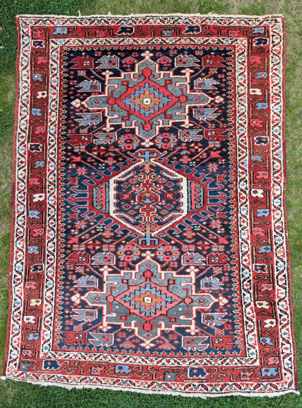 A pair of hand-knotted wool Karaja rugs featuring traditional geometric central medallions in blue, red, and ivory on an indigo field with stylized borders. View III