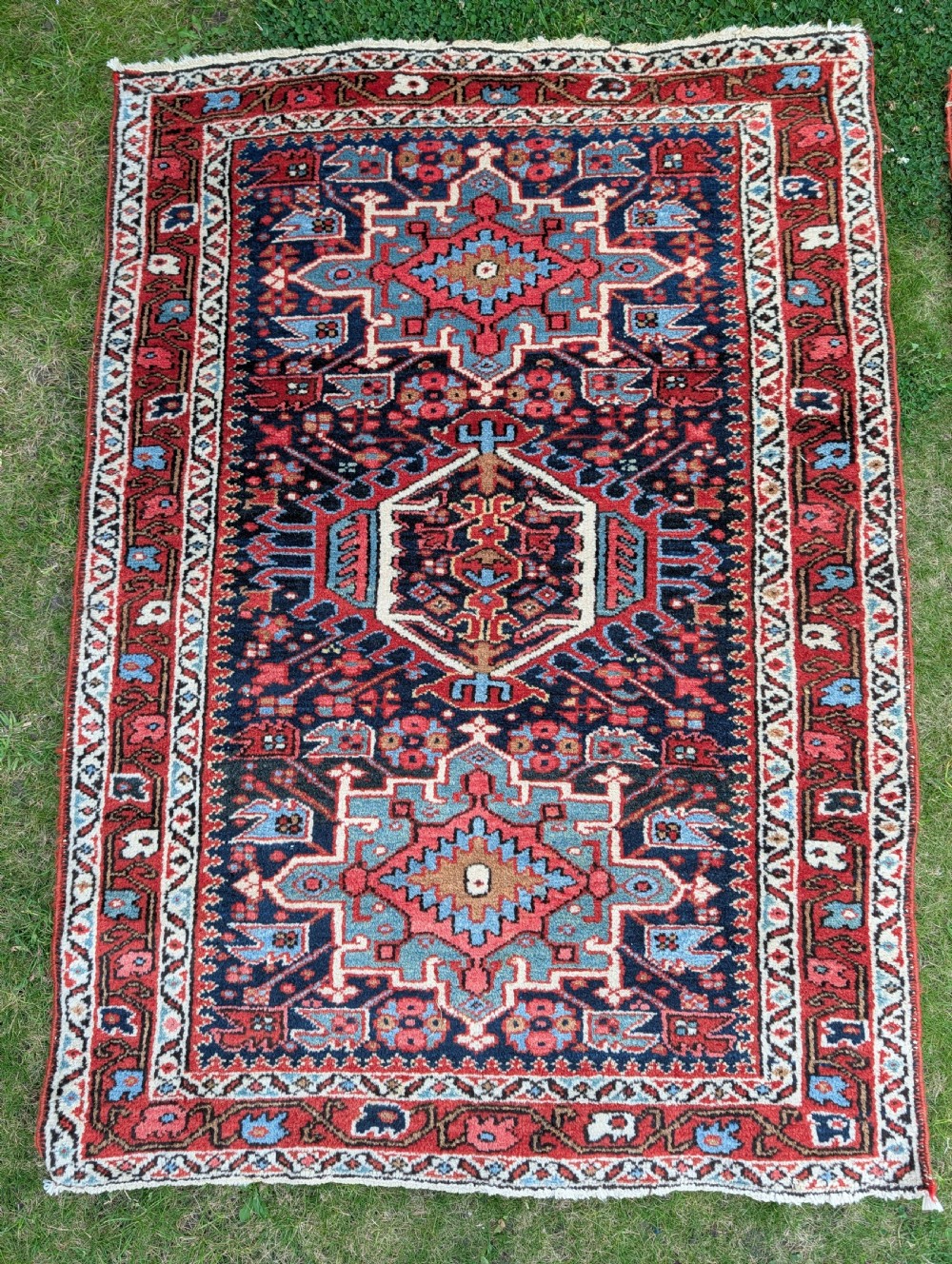 A pair of hand-knotted wool Karaja rugs featuring traditional geometric central medallions in blue, red, and ivory on an indigo field with stylized borders. View IV
