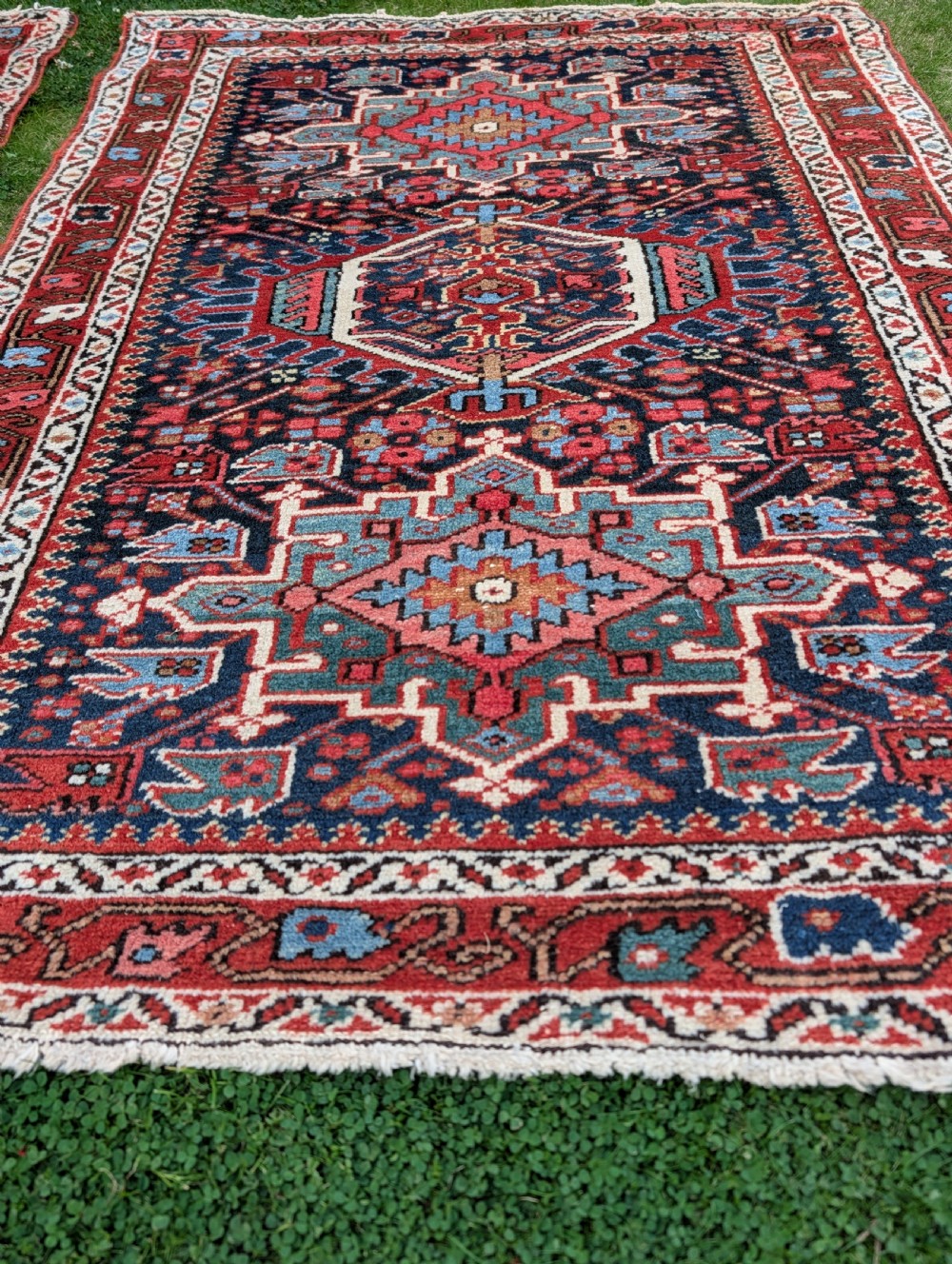 A pair of hand-knotted wool Karaja rugs featuring traditional geometric central medallions in blue, red, and ivory on an indigo field with stylized borders. View V