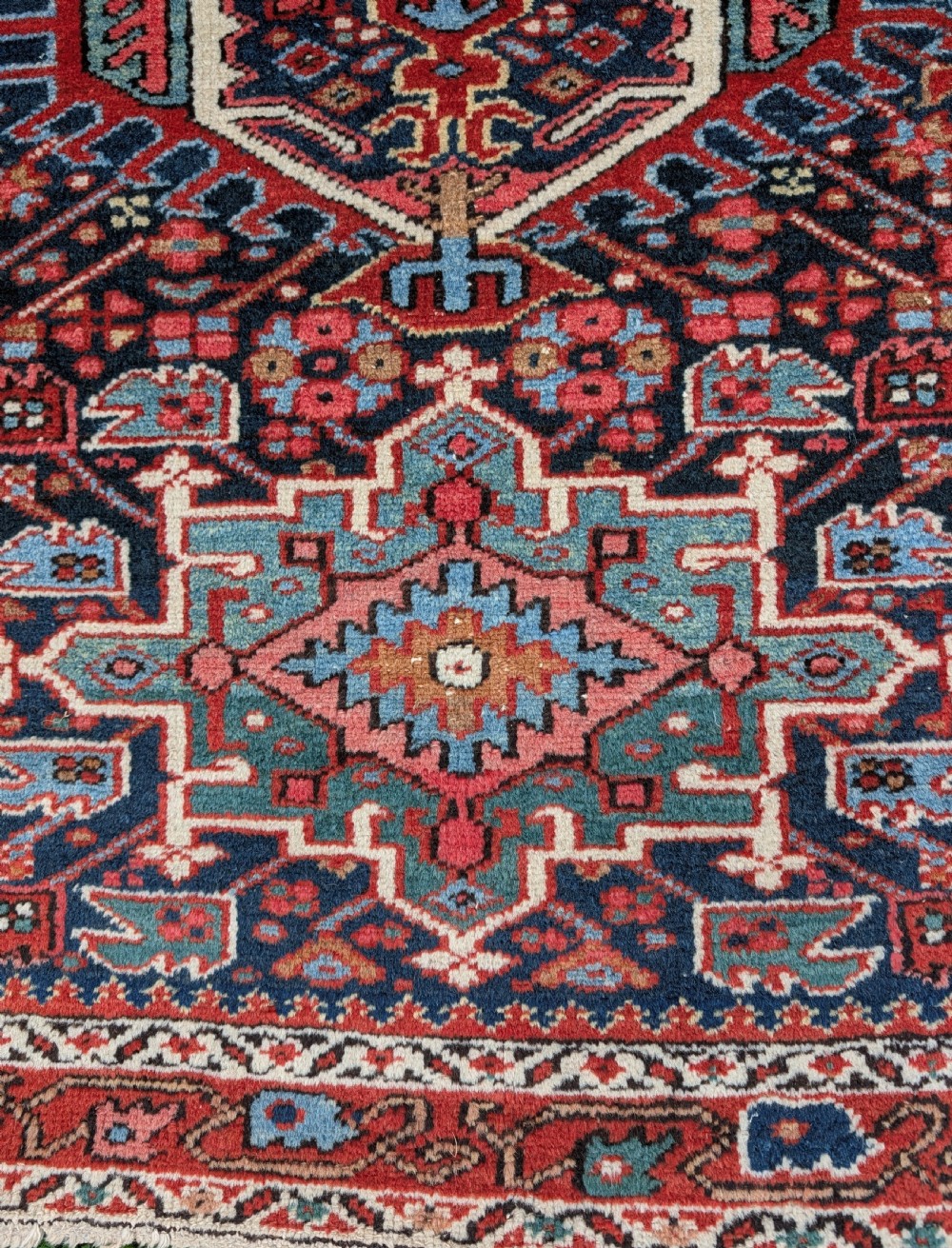 A pair of hand-knotted wool Karaja rugs featuring traditional geometric central medallions in blue, red, and ivory on an indigo field with stylized borders. View VI