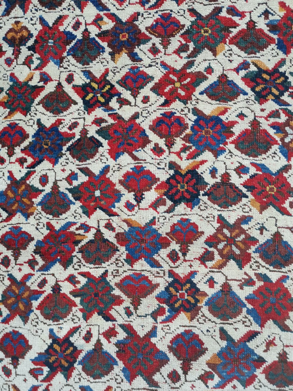 An antique hand-knotted Afshar wool rug featuring a cream field with repeating red and navy geometric motifs framed by a dark red patterned border. View II