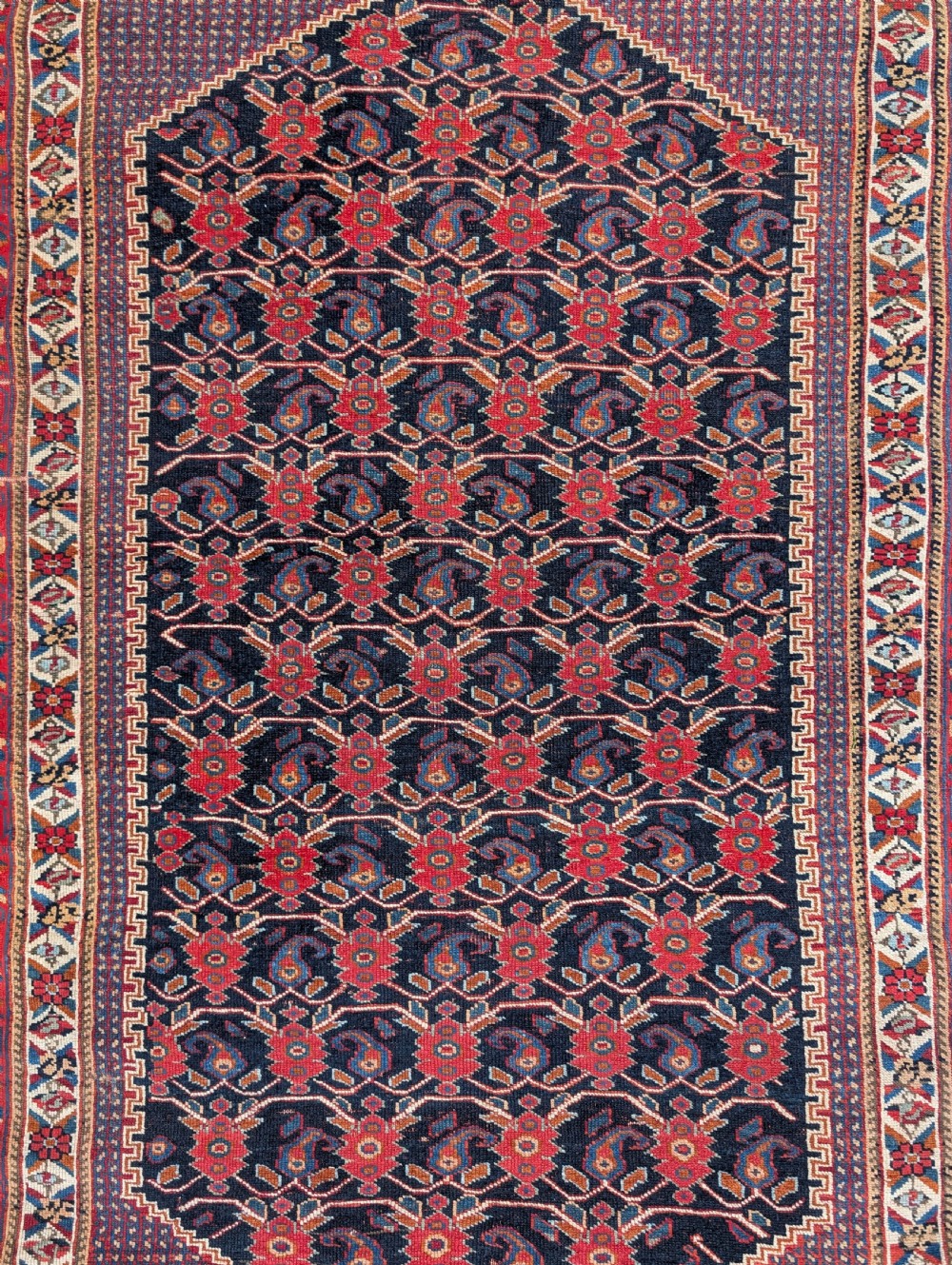 An antique hand-knotted Afshar rug featuring a navy hexagonal central field filled with red boteh motifs surrounded by ornate multi-band red borders. View II