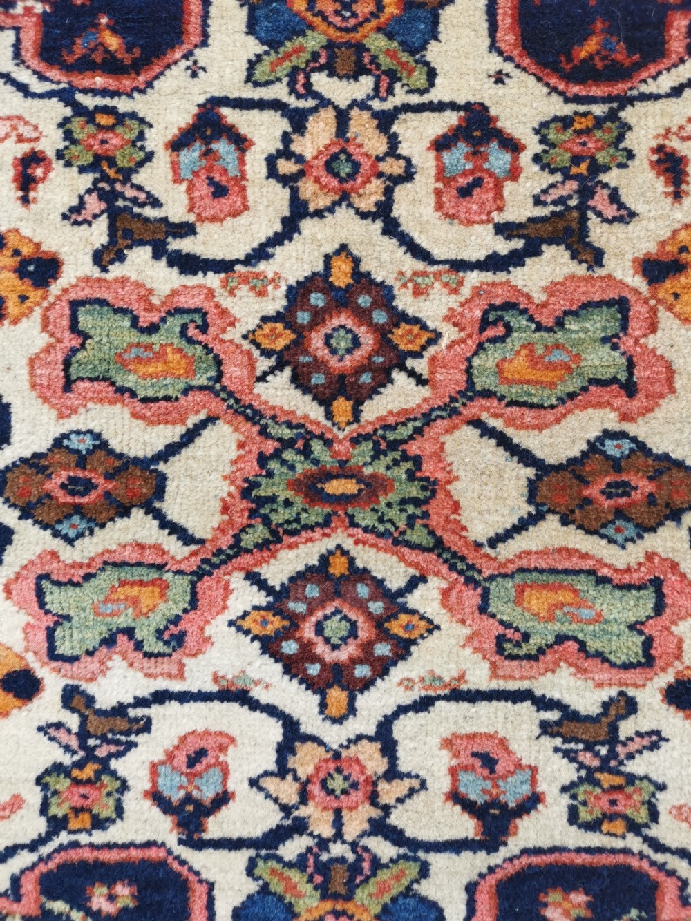 An antique hand-knotted Persian Jozan rug featuring a cream central medallion surrounded by dense floral patterns on a dark navy field with a red border. View IV