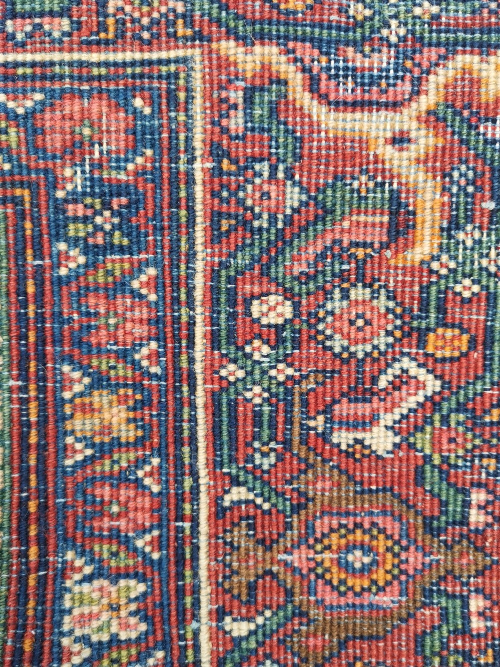 An antique hand-knotted Persian Jozan rug featuring a cream central medallion surrounded by dense floral patterns on a dark navy field with a red border. View V