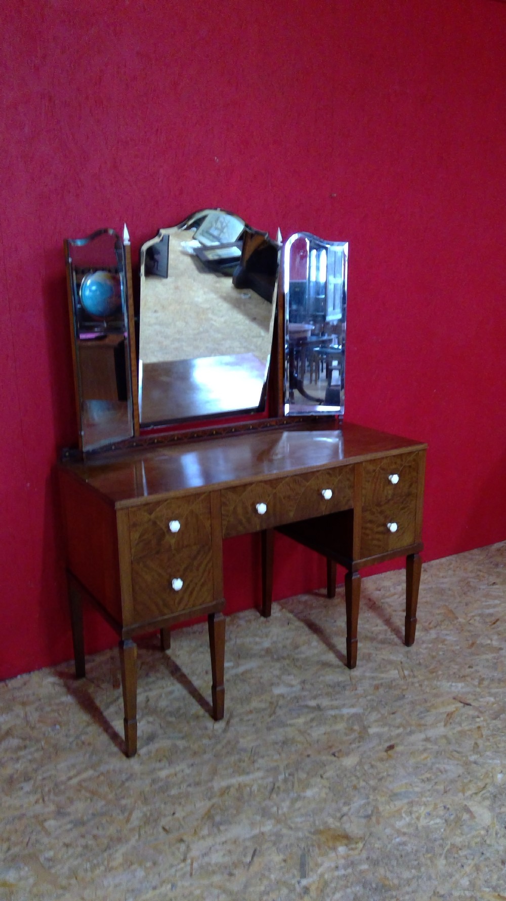 An Art Deco mahogany dressing table featuring a central mirror flanked by two adjustable wing mirrors, geometric wood inlays, and small white drawer knobs. View XI