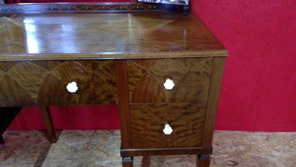 An Art Deco mahogany dressing table featuring a central mirror flanked by two adjustable wing mirrors, geometric wood inlays, and small white drawer knobs. View V