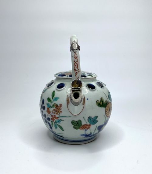 fig 1. An Edo-period Japanese Imari porcelain sake ewer featuring polychrome floral enamel patterns, an overhead handle, and metal mounts.