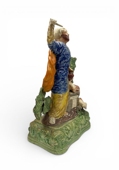 fig 1. A polychrome Staffordshire earthenware figure group depicting Abraham and Isaac on a green leaf-moulded ceramic base.