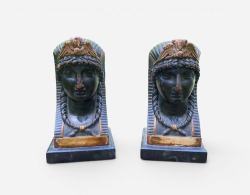 fig 1. A facing pair of carved dark wood sphinx busts with gilt highlights mounted on rectangular black marble bases.