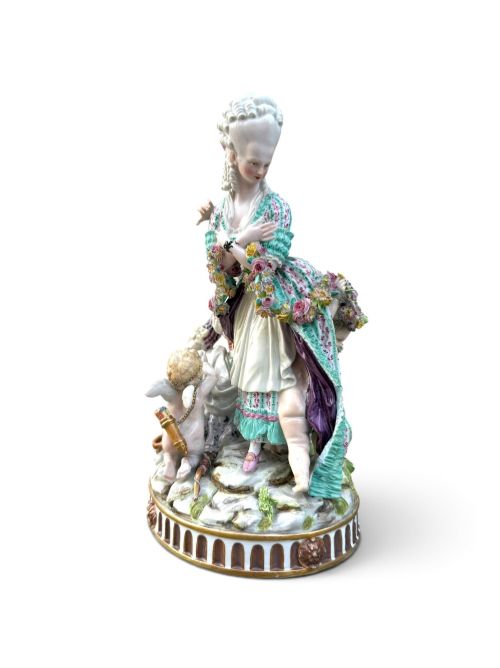 fig 1. An eighteenth-century polychrome hard-paste porcelain figurine group depicting two classical figures and a cherub beside an overturned basket of eggs on a moulded fluted base.