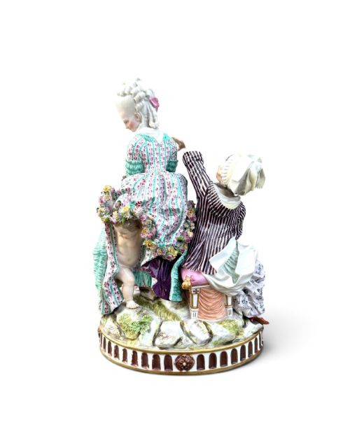 fig 3. An eighteenth-century polychrome hard-paste porcelain figurine group depicting two classical figures and a cherub beside an overturned basket of eggs on a moulded fluted base.