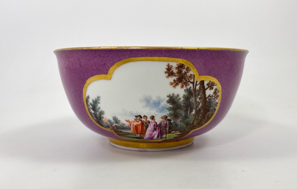 A deep porcelain bowl with a vibrant puce exterior featuring a shaped gilded frame around a hand-painted scene of two figures outdoors. View II