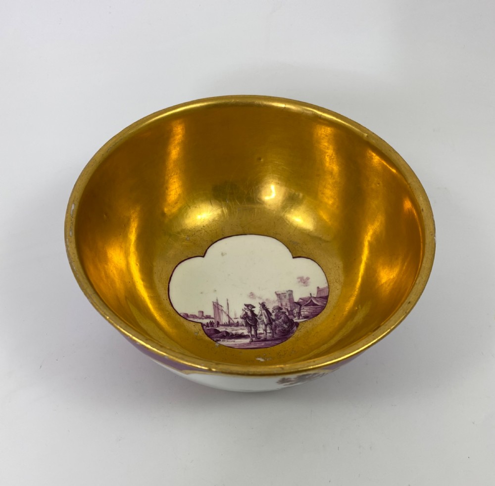 A deep porcelain bowl with a vibrant puce exterior featuring a shaped gilded frame around a hand-painted scene of two figures outdoors. View VI
