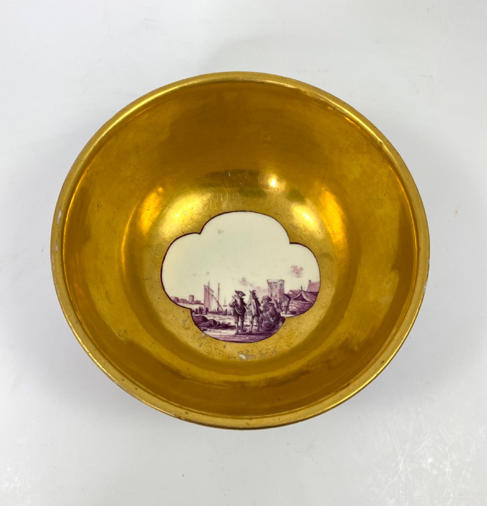 A deep porcelain bowl with a vibrant puce exterior featuring a shaped gilded frame around a hand-painted scene of two figures outdoors. View VII