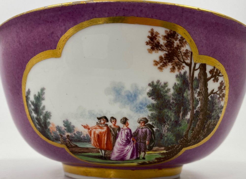 A deep porcelain bowl with a vibrant puce exterior featuring a shaped gilded frame around a hand-painted scene of two figures outdoors. View IX