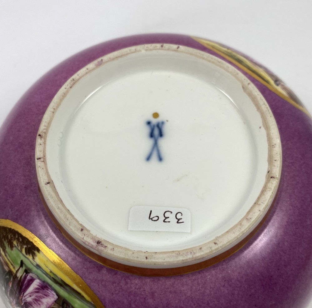 A deep porcelain bowl with a vibrant puce exterior featuring a shaped gilded frame around a hand-painted scene of two figures outdoors. View XI