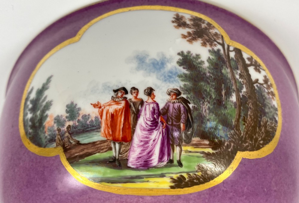 A deep porcelain bowl with a vibrant puce exterior featuring a shaped gilded frame around a hand-painted scene of two figures outdoors. View XIII