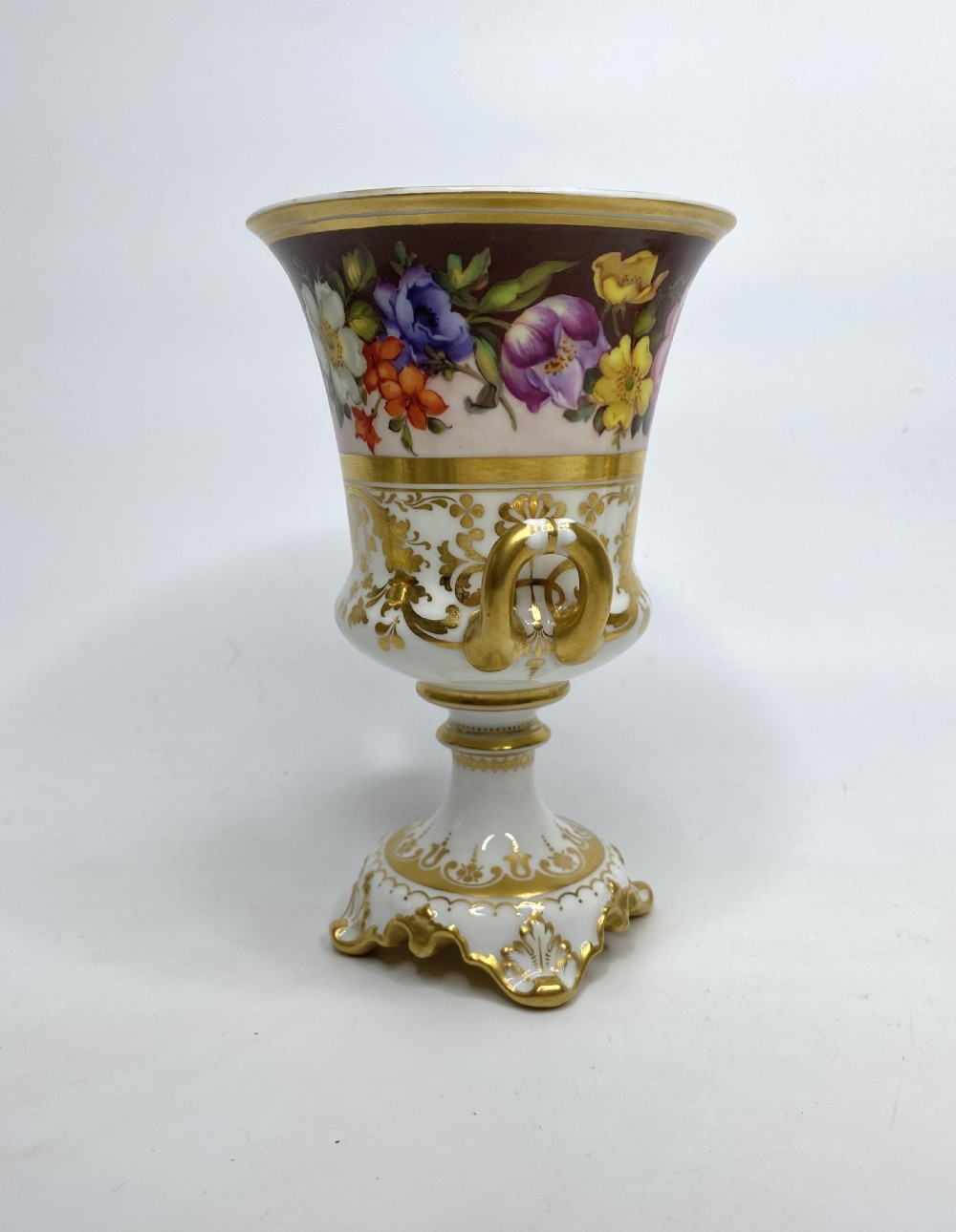A pair of Royal Crown Derby porcelain urns featuring elaborate gold scrollwork and detailed hand-painted floral bands. View VI