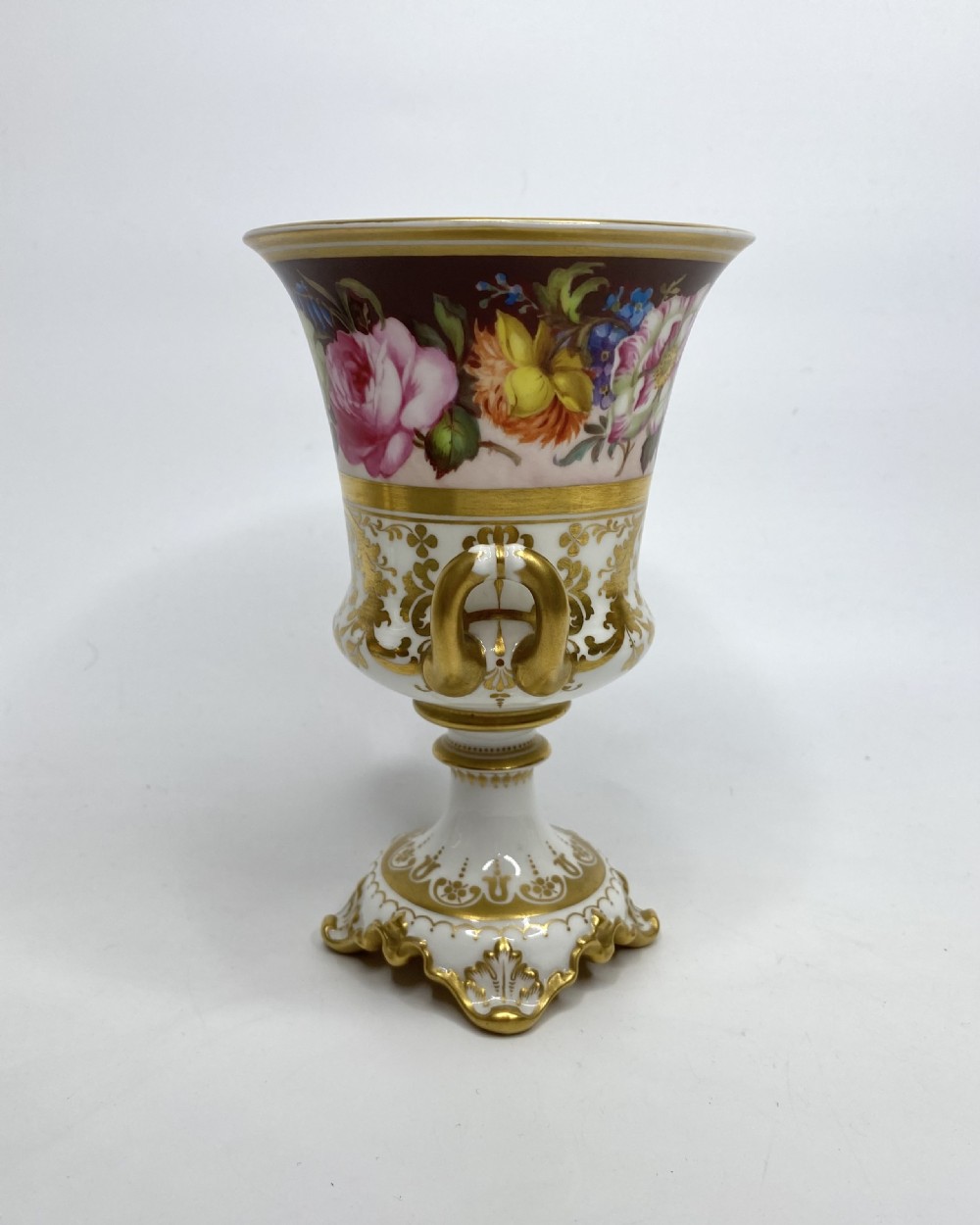 A pair of Royal Crown Derby porcelain urns featuring elaborate gold scrollwork and detailed hand-painted floral bands. View XII