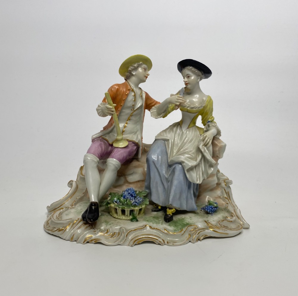 An eighteenth-century Ludwigsburg polychrome porcelain figurine group featuring a man with a wind instrument and a woman seated on a gilded rococo scroll base.