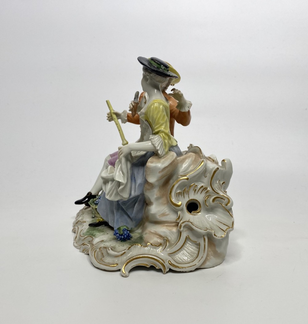 An eighteenth-century Ludwigsburg polychrome porcelain figurine group featuring a man with a wind instrument and a woman seated on a gilded rococo scroll base. View II