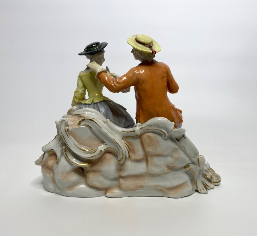 An eighteenth-century Ludwigsburg polychrome porcelain figurine group featuring a man with a wind instrument and a woman seated on a gilded rococo scroll base. View III