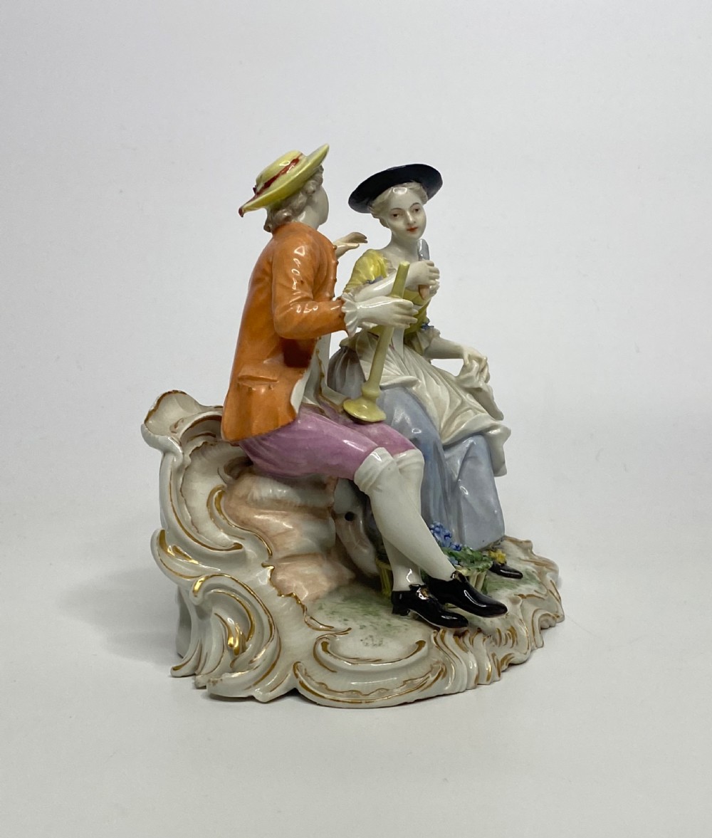 An eighteenth-century Ludwigsburg polychrome porcelain figurine group featuring a man with a wind instrument and a woman seated on a gilded rococo scroll base. View IV