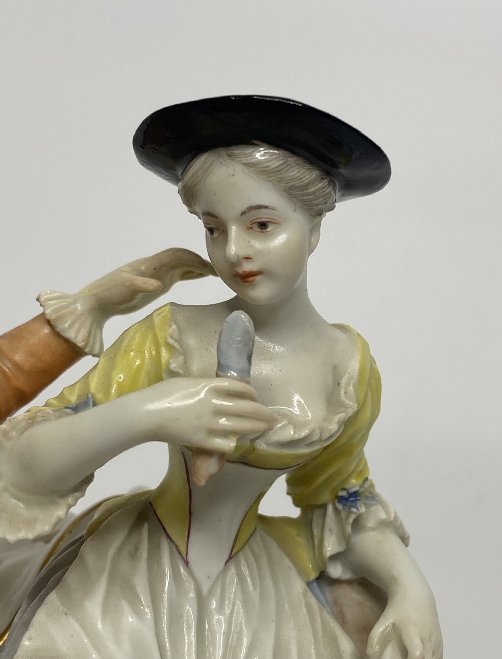An eighteenth-century Ludwigsburg polychrome porcelain figurine group featuring a man with a wind instrument and a woman seated on a gilded rococo scroll base. View V