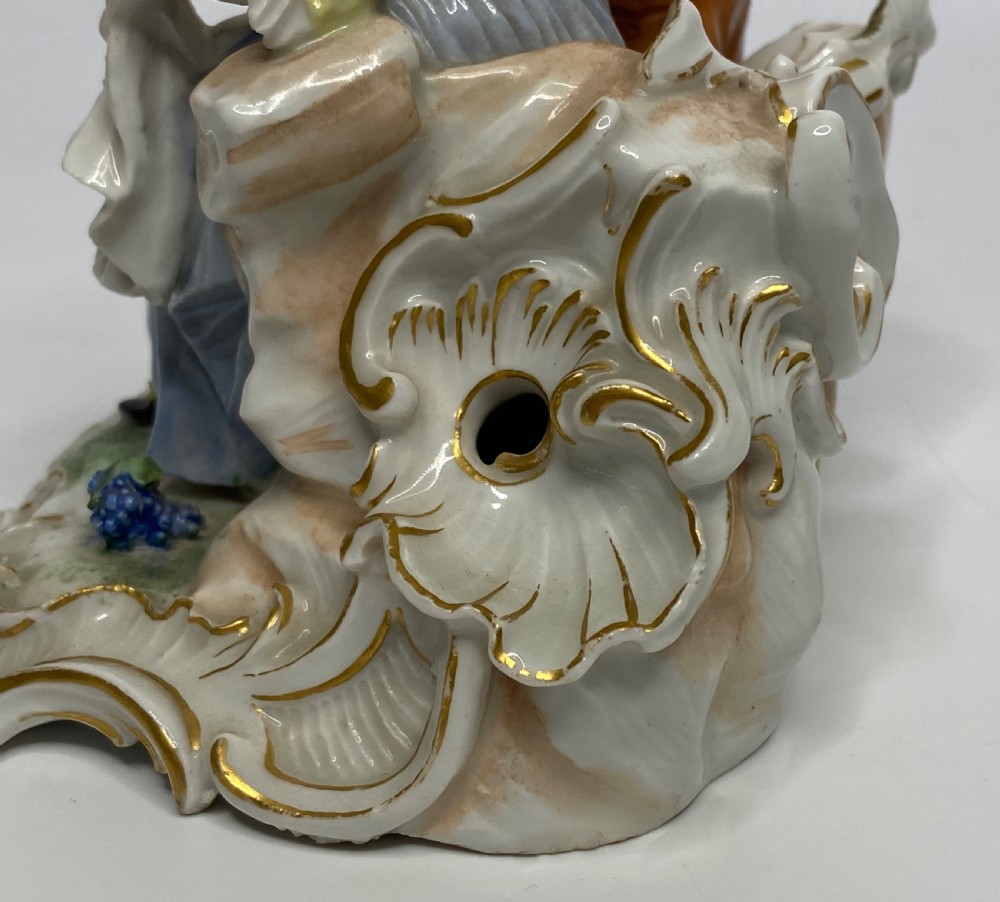 An eighteenth-century Ludwigsburg polychrome porcelain figurine group featuring a man with a wind instrument and a woman seated on a gilded rococo scroll base. View X